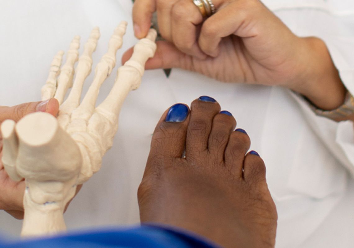 Doctor pointing to a model of a foot next to a patient's foot